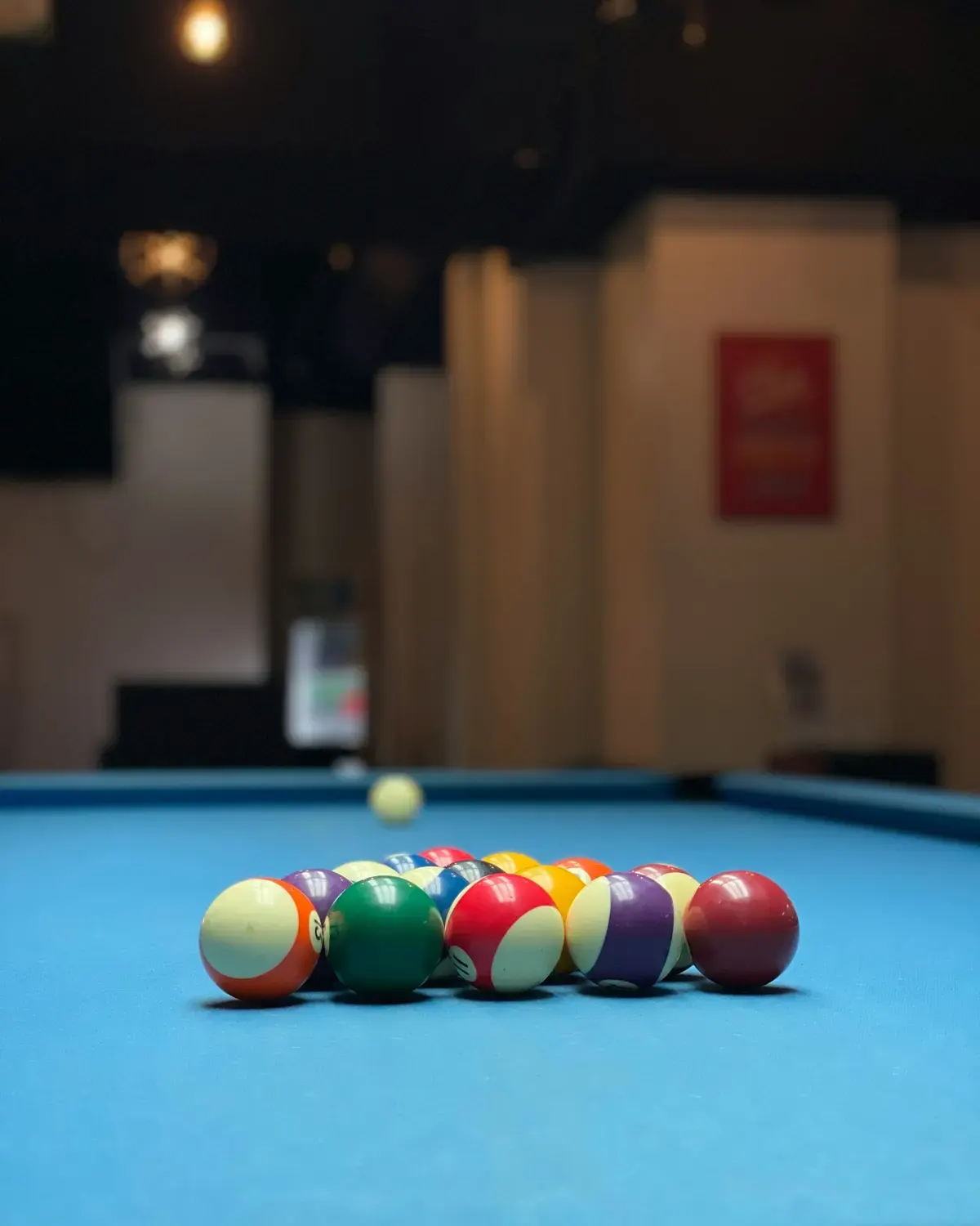 Racked balls on a blue pool table in a dim lounge