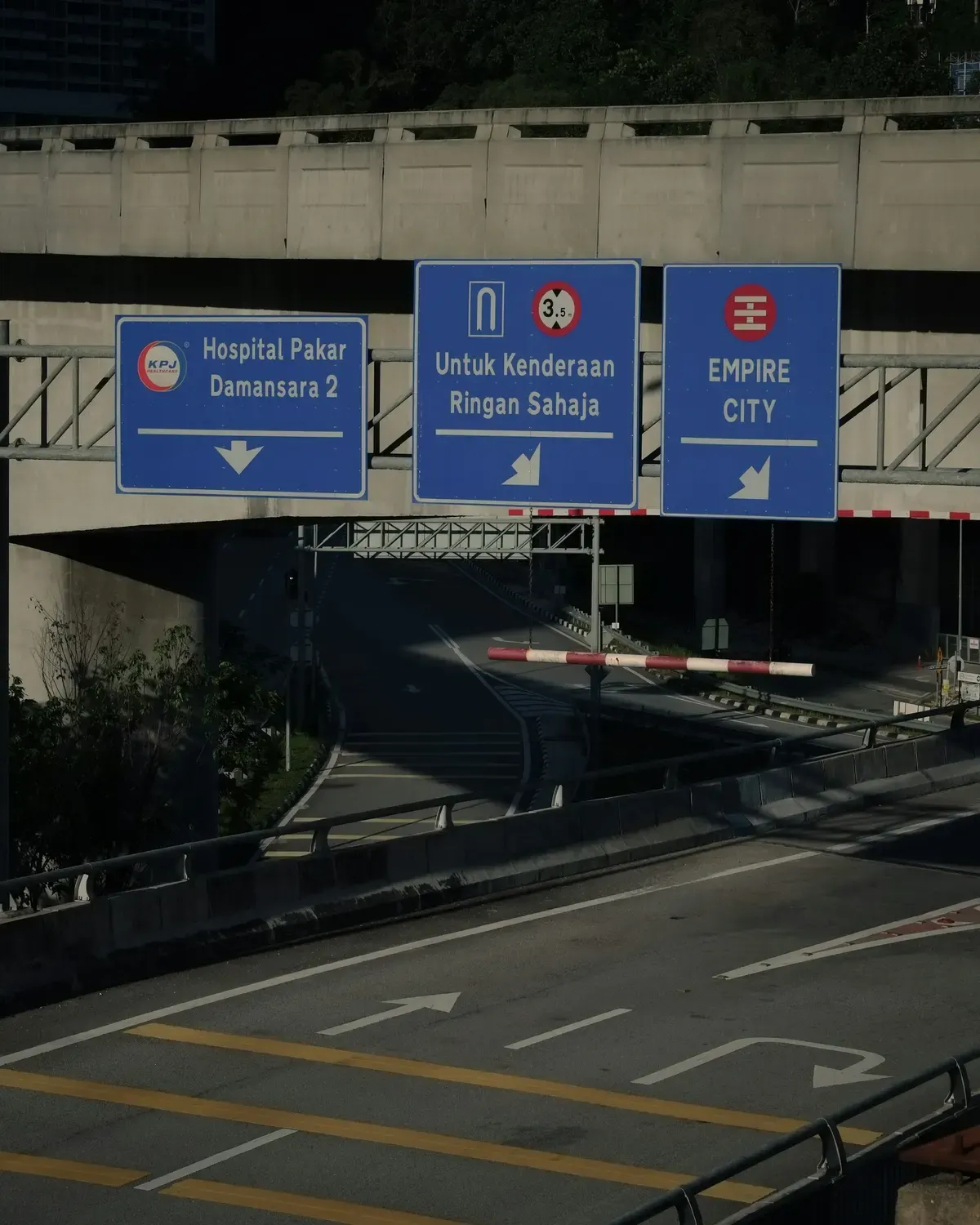 Overhead road signs pointing towards Empire City and a Damansara hospital