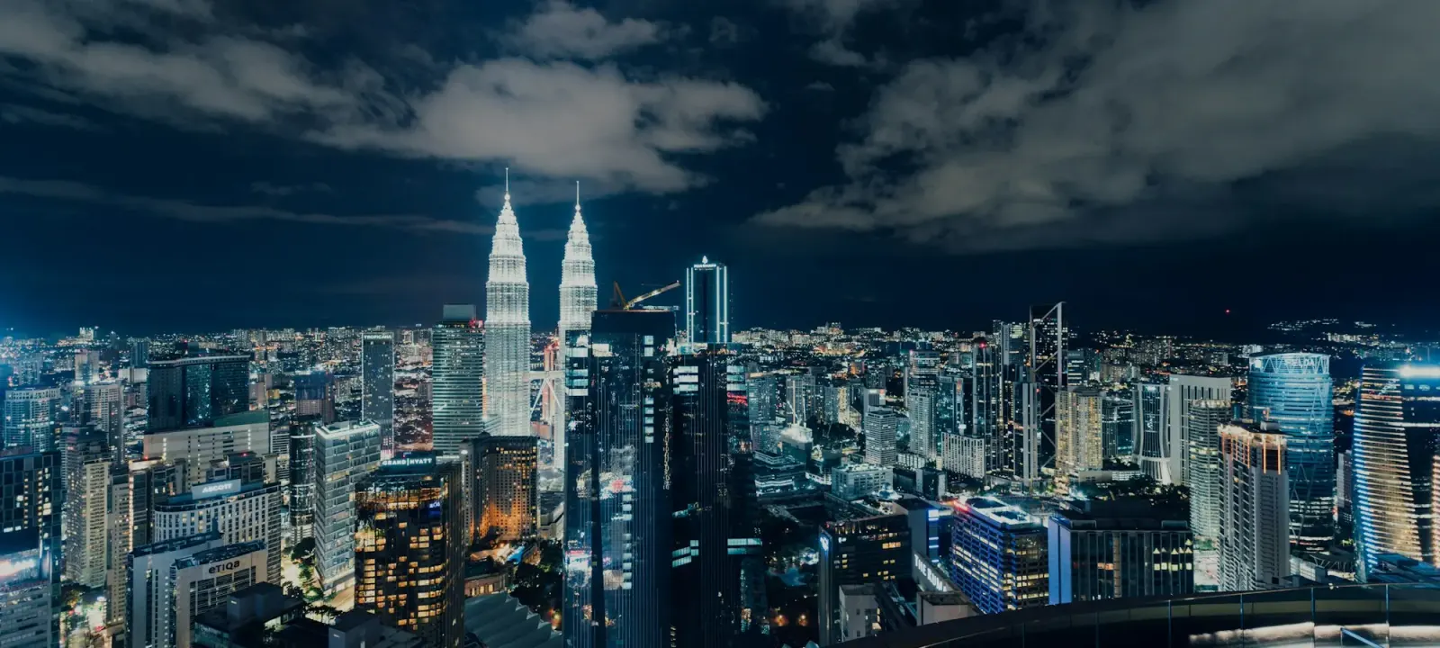 The Kuala Lumpur skyline and the Twin Towers under a cloudy night sky
